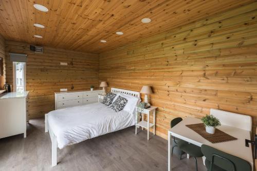 a bedroom with a bed and a wooden wall at Tan Y Fron By Birch Stays in Pentraeth