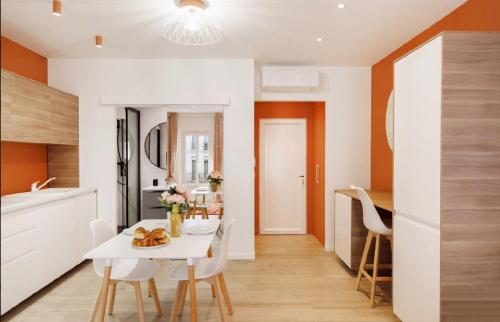 une cuisine et une salle à manger avec une table et des chaises blanches dans l'établissement Studio Orange, Hypercentre à 2minutes du Palais des congrès, à Cannes