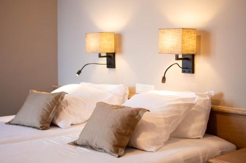 two lamps on a bed with white pillows at Ambassador Hotel in De Panne