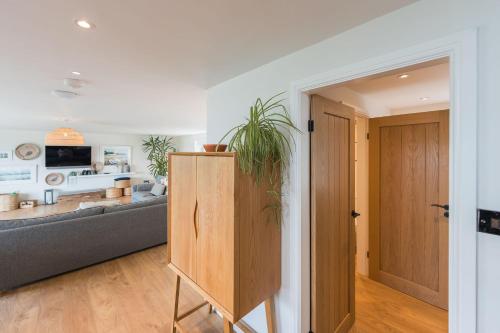 a living room with a couch and a potted plant at Tan Y Fron By Birch Stays in Pentraeth