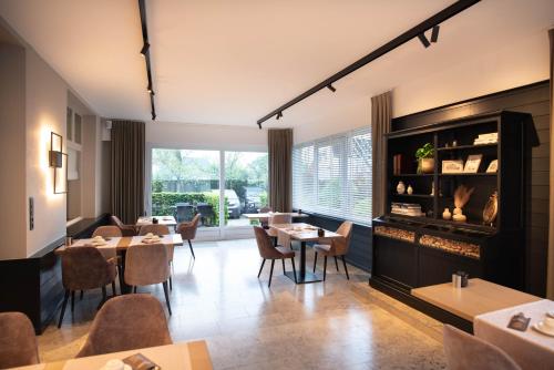 a restaurant with tables and chairs and a large window at Ambassador Hotel in De Panne