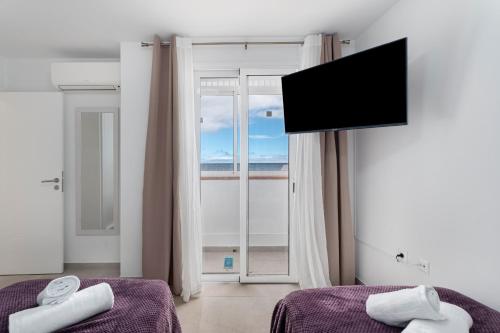 a room with two beds and a flat screen tv at Villa Atlantico in Candelaria