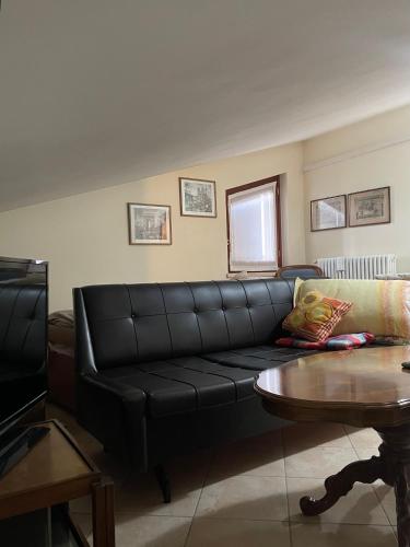 a living room with a black leather couch and a table at Villa Rondine in Corno Alto