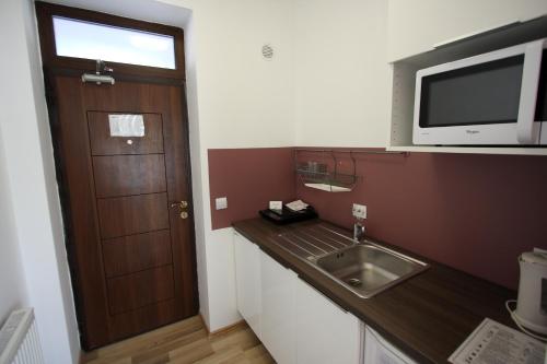 eine Küche mit einer Spüle, einer Mikrowelle und einer Tür in der Unterkunft Studio ApartCity in Braşov