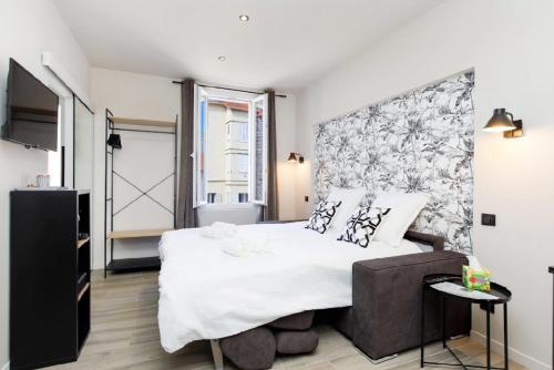 une chambre avec un grand lit blanc et une fenêtre dans l'établissement Studio N , Hypercentre à 2 minutes du Palais des congrès, à Cannes