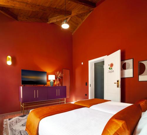 a bedroom with orange walls and a bed and a tv at Archontiko Parnassus Dadi in Amfiklia