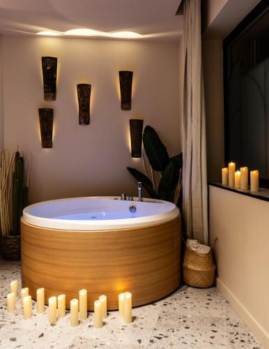 La salle de bains est pourvue d'une baignoire avec des bougies. dans l'établissement Love Room Strasbourg, Sauna, Spa, Suite Ibiza, Évasion Romantique et Sensuelle, à Strasbourg