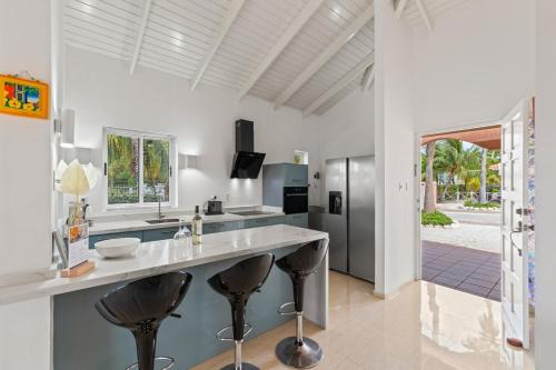 a kitchen with a large counter with stools in it at Villa 449 Piscadera in Sint Michiel