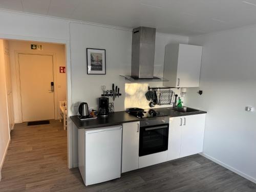 a kitchen with white cabinets and a black counter top at Höga Kusten Lägenhetshotell in Gallsätter