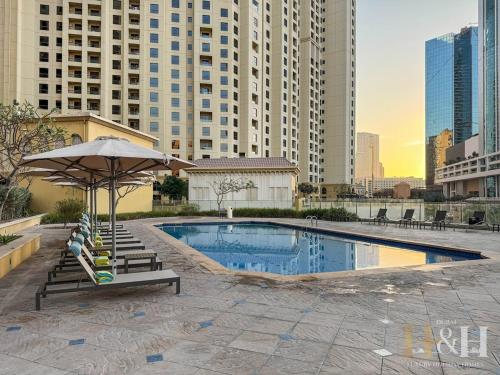 a swimming pool with lounge chairs and an umbrella at Stunning views of Dubai Sea, Dubai Eye & JBRWalk in Dubai
