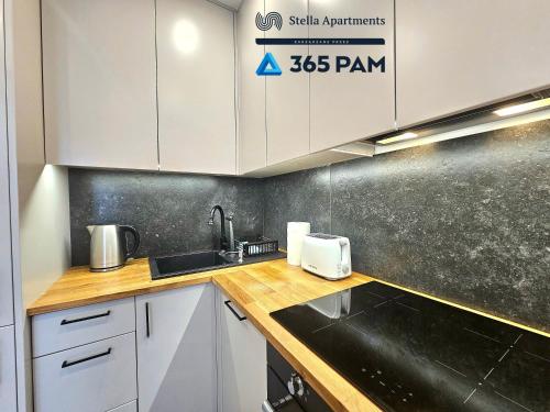 a kitchen with white cabinets and a black counter top at 365PAM - Apartament Bliżej Morza w Gąskach in Gąski