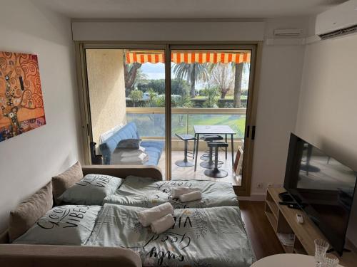 a living room with a bed and a tv and a patio at Dionysos in Cannes