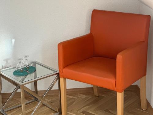 an orange chair next to a glass table at Hotel Haus am Ahorn in Schöneck
