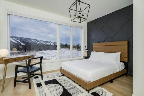 a bedroom with a bed and a desk and a window at The Luxury Black Rose Chalet at The Blue Mountains for 20 in Blue Mountains