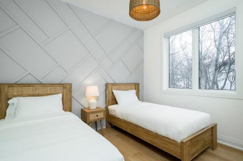 two beds in a white room with a window at White Rose Chalet at Blue Mountains for 20 w Hot Tub in Blue Mountains