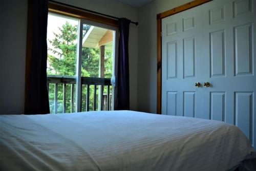 a bedroom with a bed and a door with a window at The Blue Mountains Chalet for 20- 8BR Bliss w Hot Tub in Blue Mountains