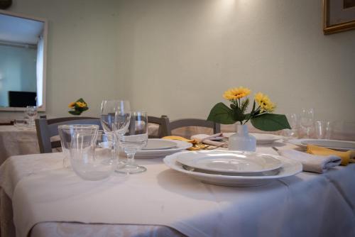 a table with plates and glasses and a vase with flowers at Hotel Eden in Arenzano