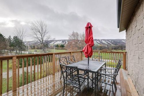 a table with chairs and an umbrella on a deck at Glacial Getaway at The Blue Mountains w HTub for 18 in Blue Mountains