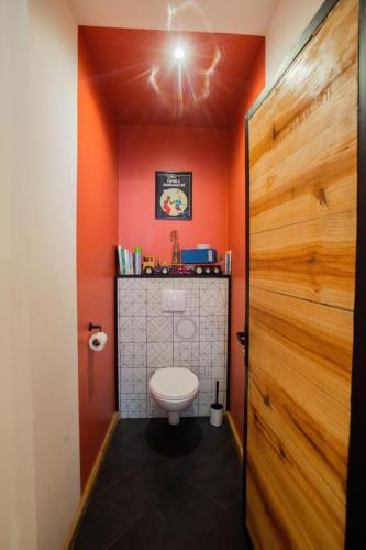 a bathroom with a toilet and an orange wall at Joyau secret # Jardin # Piscine # Bien-être # prox centre ville in Antananarivo