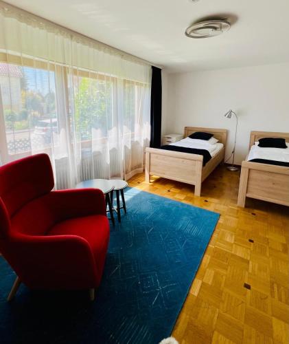 a living room with two beds and a red chair at Gästehaus 24 Jettingen EG in Jettingen
