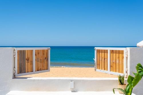 an open door to the beach with the ocean in the background at Beach front right on the Sand Luxury semi-detached 3 bed Villa in Faro