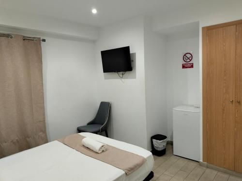 une chambre avec un lit, une chaise et une télévision dans l'établissement Pensión Portugal, à Alicante