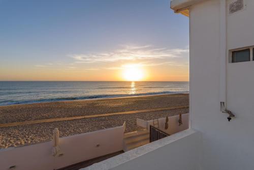 a view of the beach at sunset from a building at Beach front right on the Sand Luxury semi-detached 3 bed Villa in Faro