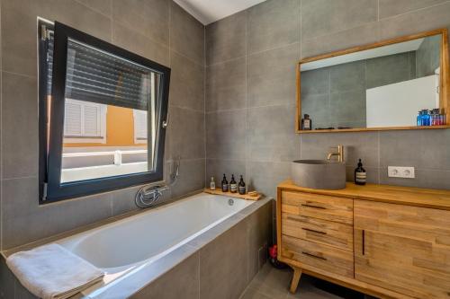 a bathroom with a tub and a window and a sink at Beach front right on the Sand Luxury semi-detached 3 bed Villa in Faro