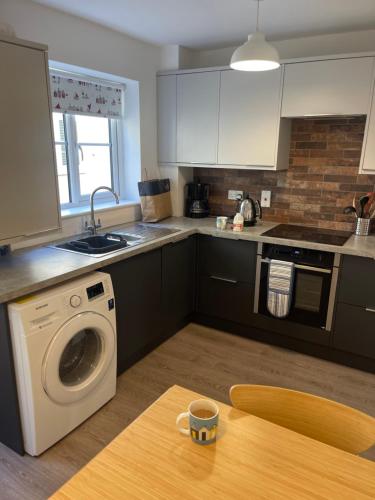 a kitchen with a washing machine and a wooden table at Avocet Cottage Sheringham in Sheringham