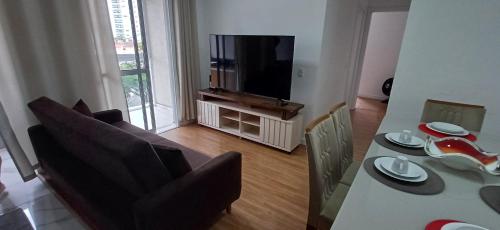 a living room with a dining table and a television at AP no Centro, Ao lado de Praça de Poços de Caldas in Poços de Caldas
