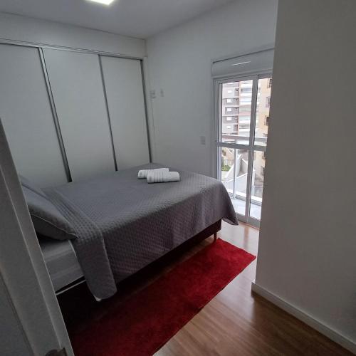 a bedroom with a bed and a large window at AP no Centro, Ao lado de Praça de Poços de Caldas in Poços de Caldas