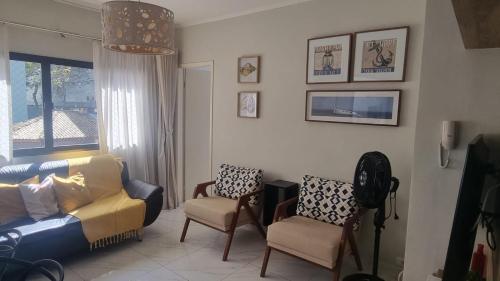 una sala de estar con un sofá y dos sillas en Apartamento no Tombo 30 metros da praia, en Guarujá