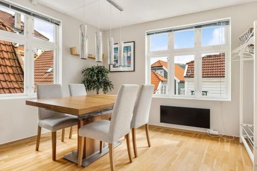 a dining room with a table and chairs and windows at Dinbnb Apartments I Historical Two-Floor Apartment with Rooftop Panorama I 1645 Heritage in Bergen