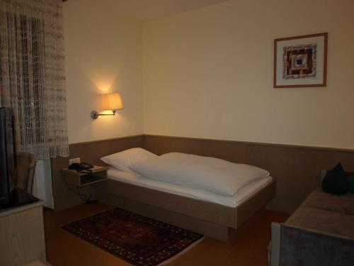 a small bedroom with a bed and a lamp at Hotel Astoria in Bergrheinfeld