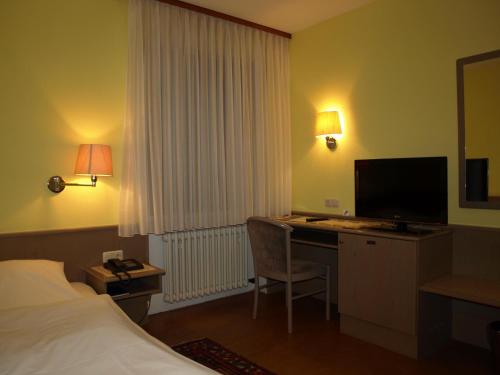 a hotel room with a bed and a desk with a computer at Hotel Astoria in Bergrheinfeld