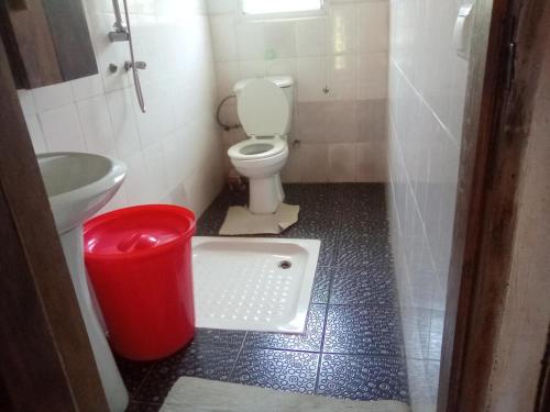 a bathroom with a toilet and a red trash can at Villa Hortansia in Nosy Be