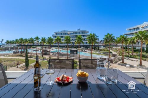 a table with a bottle of wine and a bowl of food at Luxury beachfront 3BR in Nereidas with Pools Spa Gym in Torremolinos