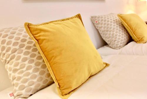 a yellow pillow sitting on a bed with two pillows at Casa do Carmo Fuzeta by Junto ao Mar in Fuzeta
