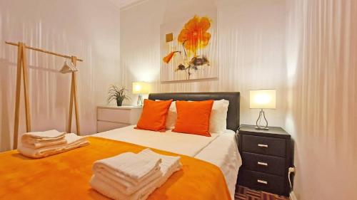 a bedroom with a large bed with orange pillows at Casa do Carmo Fuzeta by Junto ao Mar in Fuzeta
