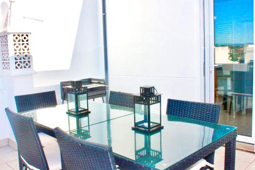 a glass dining room table with chairs and a window at Casa do Carmo Fuzeta by Junto ao Mar in Fuzeta