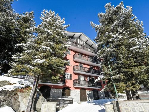 a pink apartment building with trees in the snow at Apartment Casa Rossa by Interhome in Madesimo