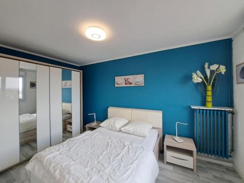 - une chambre bleue avec un lit blanc et un mur bleu dans l'établissement Ajaccio, cadre confortable avec balcon, à Reims