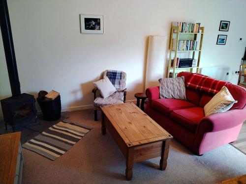 a living room with a red couch and a coffee table at The Old Bakehouse in Newcastleton