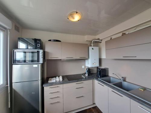 une cuisine avec des armoires blanches et un réfrigérateur en acier inoxydable dans l'établissement Ajaccio, cadre confortable avec balcon, à Reims