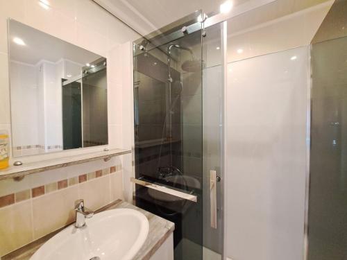 une salle de bain avec un lavabo et une douche en verre dans l'établissement Ajaccio, cadre confortable avec balcon, à Reims