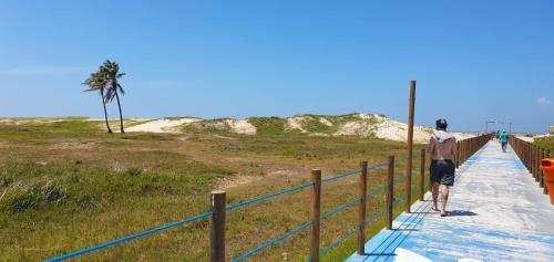 a man standing on a walkway at the beach at Hotel Da Orla in Aracaju