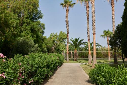 a path in a park with palm trees and flowers at Atlantica Thalassa Hotel in Kos Town