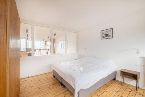a white bedroom with a bed and a mirror at Top Floor New Duplex Stunning View In Trendy St Gilles in Brussels