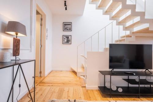 a living room with a tv and a staircase at Top Floor New Duplex Stunning View In Trendy St Gilles in Brussels