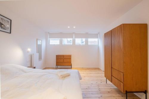 a bedroom with a large bed and a wooden cabinet at Top Floor New Duplex Stunning View In Trendy St Gilles in Brussels
